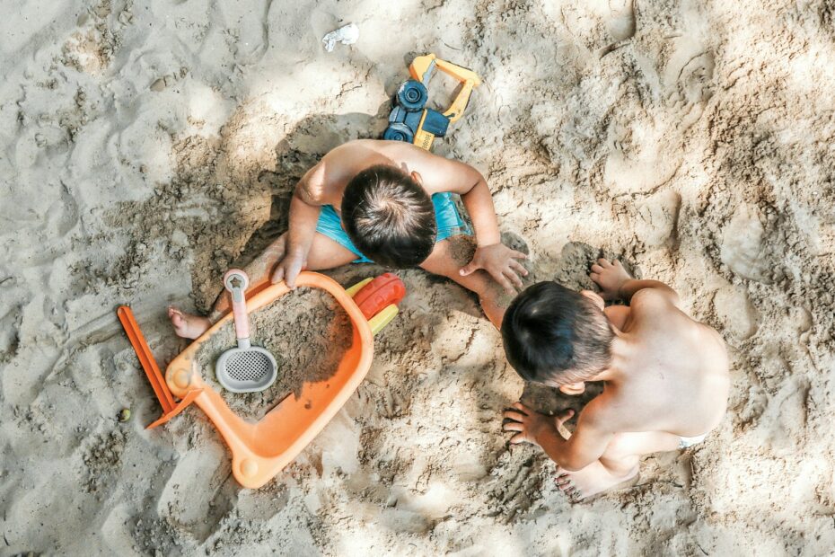 2 boys sitting on sand