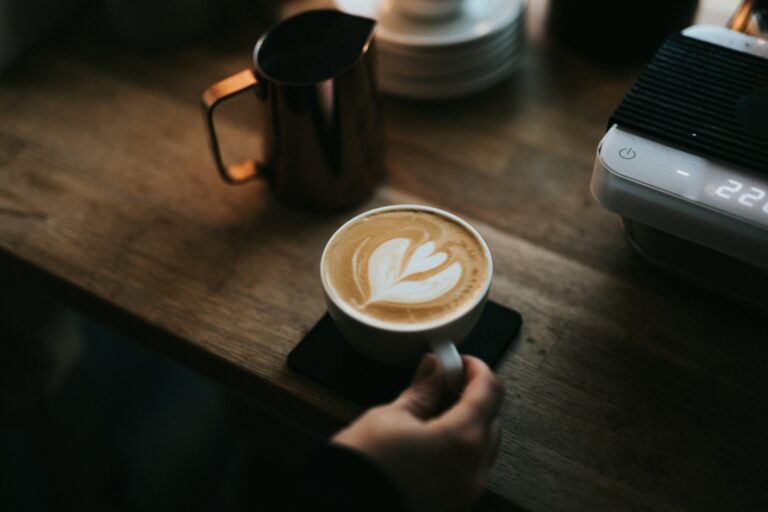 a person holding a cup of coffee on top of a wooden table