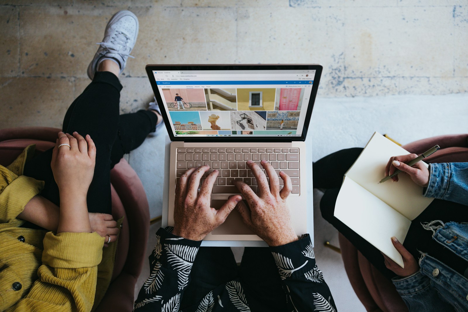 person using microsoft surface laptop on lap with two other people